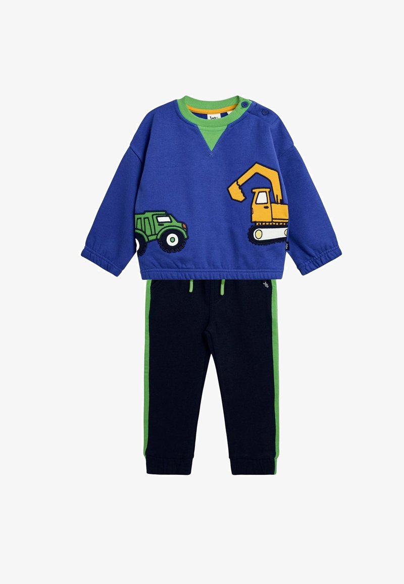 Zils džemperis ar zaļiem akcentiem, uz kura attēloti kravas auto un ekskavatora grafikas, savienots ar tumši ziliem biksēm ar zaļām sānu svītrām.