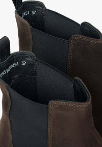 Brązowe zamszowe botki Chelsea z elastycznymi panelami bocznymi, szytymi detalami i gładką skórzaną wyściółką. Widoczne etykiety wewnętrzne wskazujące rozmiar 37.