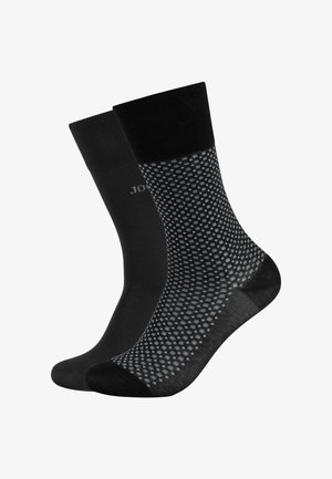 Czarne skarpetki o gładkiej fakturze, jedna jednolita, a druga z szarym kropkowanym wzorem. Obie mają wzmocniony palec i mankiet.