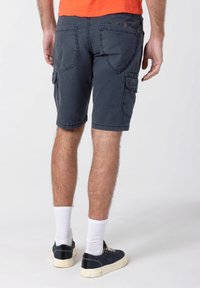 Navy cargo shorts made from durable fabric, featuring multiple pockets, stitched detailing, and a relaxed fit, paired with white socks and sneakers.