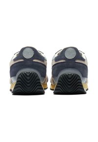 Zadní pohled na tenisky kombinující šedou a námořnickou zamšovou textilii, texturované detaily a černou gumovou podrážku se zigzagovým vzorem.