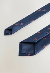 Marineblaues Seidenkrawatte mit strukturiertem Finish, das ein wiederholtes Muster von roten Flamingos und subtilen Streifen aufweist. Glatte Kanten und spitze Enden.