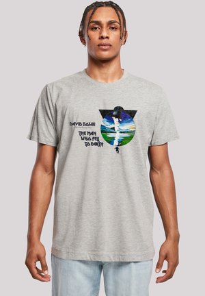 Graues Baumwoll-T-Shirt mit Rundhalsausschnitt. Auf der Vorderseite befindet sich eine bunte Grafik einer Figur mit Hut vor einer Landschaft, mit Text darunter.