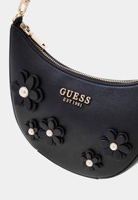 Borsa a spalla in ecopelle nera con hardware dorato, caratterizzata da applicazioni floreali e dettagli in perle. Chiusura con cerniera nella parte superiore.