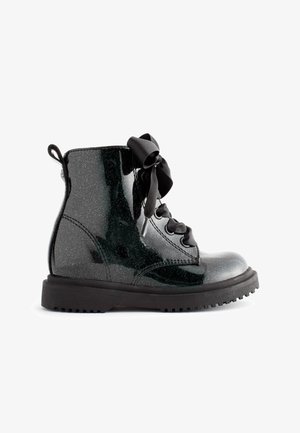 Bottines noires scintillantes avec une finition en vernis, bout rond, semelle épaisse et lacets en satin. Anse à l'arrière pour un enfilage facile.