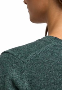 Maglione lavorato a maglia di colore verde scuro, con scollo a girocollo e maniche raglan. Il materiale sembra morbido con una finitura texture.