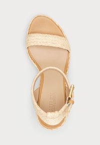 Béžová espadrilová sandála s pletenými popruhmi, plochou tkanou jútovou podrážkou a koženou stielkou s jemným logo odtlačkom. Zlatá spona ako dekorácia.