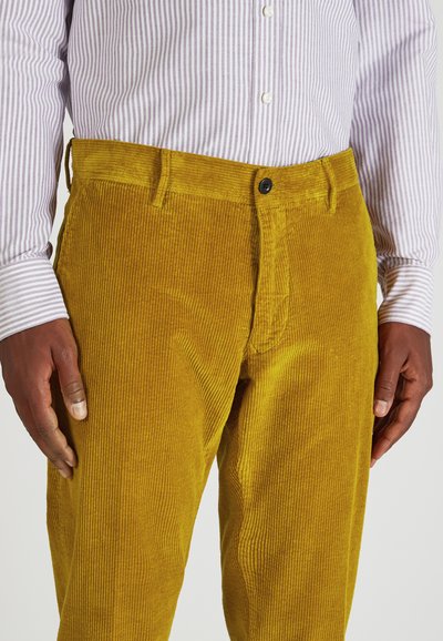 Geel corduroy broek met een ribbelstructuur, gecombineerd met een lichtpaarse gestreepte shirt. Voorzien van een knoopsluiting en zijzakken.