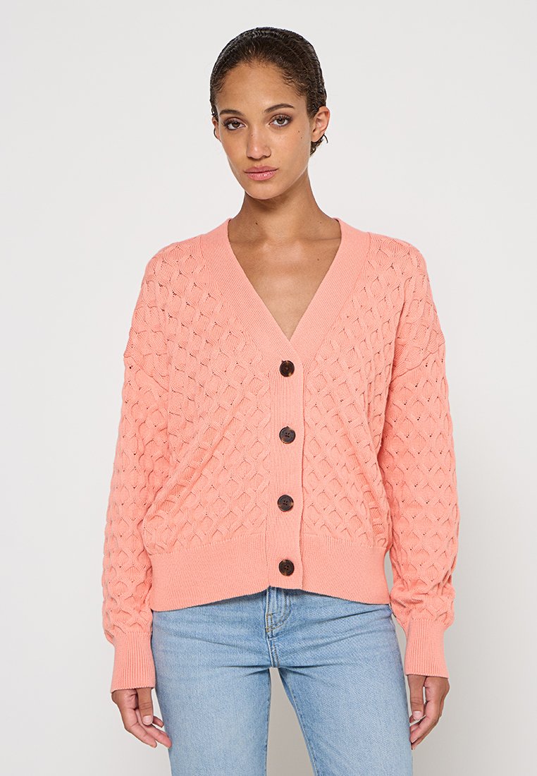 Jasnoróżowy kardigan z dzianiny o textured wzorze, z dekoltem w serek i ciemnymi guzikami, z długimi rękawami i luźnym krojem.