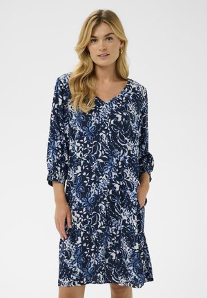 Abito a stampa floreale in blu navy e bianco, con scollo a V, maniche a tre quarti con polsini elastici e tasche laterali. Tessuto morbido.