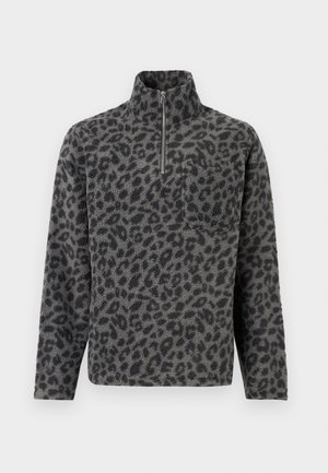 Sivý fleece pulóver s čiernym leopardím vzorom, s golierom na zips a vreckom na ľavej strane hrude. Mäkká textúra, dlhé rukávy, voľný strih.
