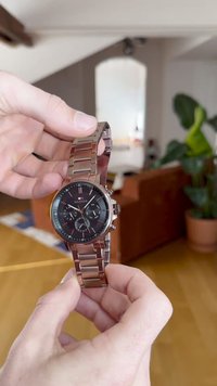 Ασημένιο ρολόι από ανοξείδωτο ατσάλι με μαύρο καντράν, χαρακτηριστικά χρονογράφου και βραχιόλι από συνδέσμους. Περιλαμβάνει κόκκινες λεπτομέρειες και πολλαπλά καντράν.