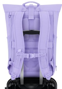Lila hátizsák ergonomikus, párnázott pántokkal és hálós hátrésszel. Magában foglal egy felső fogantyút, és rögzíthető egy fekete kerekes bőröndhöz.