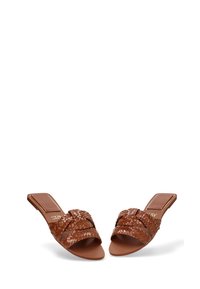 Sandalias deslizantes trenzadas de color marrón con suela plana. La parte superior presenta correas cruzadas y un acento en el talón rectangular y suave.