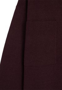 Pulover bordeaux dintr-o țesătură cu detalii în stil ribbed la buzunar. Textură moale cu o finisare netedă, prezentând o croială relaxată și un design minimalist.