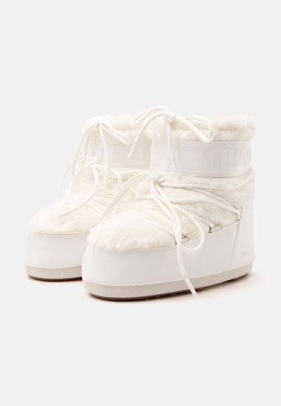 Paire de bottes d'hiver blanches rembourrées avec doublure en fourrure, lacets et bracelets de cheville de marque, présentées sur un fond clair uni.
