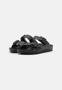Schwarze Sandalen mit zwei verstellbaren Riemen und Schnallen, ausgestattet mit einem strukturierten Fußbett und einer soliden Gummisohle für besseren Grip.