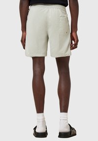 Light beige shorts with an elastic waistband, back pocket, and hem that falls mid-thigh. Fabric appears smooth with a subtle texture.