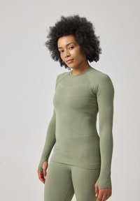 Helle grüne langärmlige Sportoberteil mit figurnaher Passform und strukturiertem Stoff. Verfügt über Daumenlöcher und einen runden Halsausschnitt für zusätzlichen Komfort.