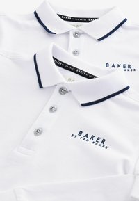 Weiße Poloshirts mit navyfarbenem Besatz, ausgestattet mit drei Knöpfen und einem strukturierten Stoff. "BAKER by TED BAKER"-Logo in navyfarbener Stickerei auf der Brust.