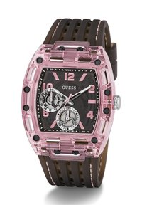 Montre avec boîtier transparent rose et bracelet en caoutchouc marron. Présente un cadran noir, de grands index horaires roses et deux sous-cadrans pour le suivi du temps.