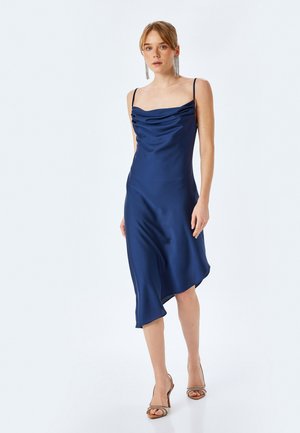 Robe en satin bleu marine avec un décolleté drapé, des bretelles spaghetti ajustables et un ourlet asymétrique. Texture lisse, quincaillerie minimale.