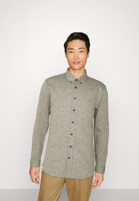 Camisa de manga larga con botones en una tela texturizada de color gris claro, con cuello, botones negros y un dobladillo recto.