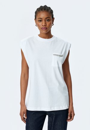 T-shirt bianco senza maniche con spalline, caratterizzato da una tasca sul petto decorata con dettagli in catena argentata. Realizzato in morbido tessuto di cotone.