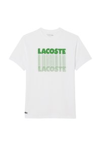 Camiseta blanca de manga corta con el texto "LACOSTE" en verde impreso dos veces en un diseño de degradado vertical en el frente, con el logo del cocodrilo de Lacoste cerca del dobladillo.