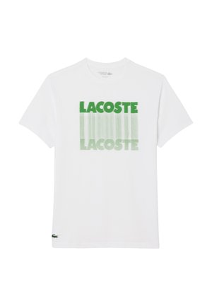 Witte T-shirt met korte mouwen, met groen "LACOSTE"-tekst die twee keer in een verticale vervagingsontwerp op de voorkant is bedrukt, met het Lacoste krokodil logo nabij de zoom.