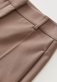 Braun strukturierter Stoff mit glatter Oberfläche, ausgestattet mit einem Standardbund und seitlichen Taschendetails. Saubere Nähte und lässiges Design.