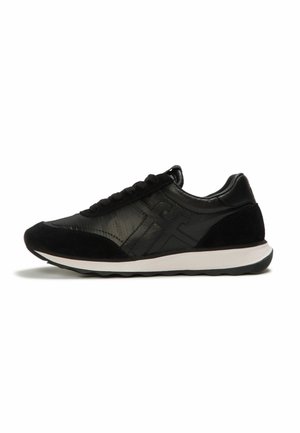 Zwarte lage sneaker met veters aan de voorkant, suède en leren panelen, en witte rubberen zool met zwart profiel.