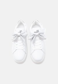 Λευκά αθλητικά παπούτσια με ομαλή υφή από δέρμα, στρογγυλεμένο σχήμα μύτης και εμφανή ασημένια διακοσμητικά φιόγκους με στρας στα κορδόνια.