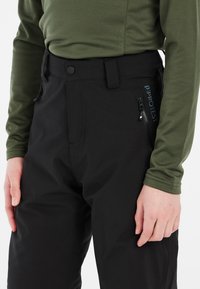Pantaloni neri impermeabili con un design elegante, dotati di chiusura con bottone, tasche con zip e un logo ricamato sul lato.