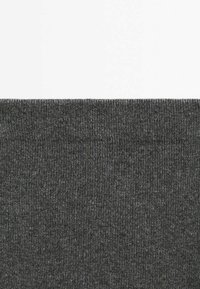 Tissu tricoté côtelé gris foncé avec une texture horizontale remplissant la moitié inférieure du cadre sur un fond blanc uni.