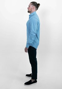 Gestreept blauw shirt van katoen, met een puntkraag en lange mouwen, gecombineerd met donkere broeken en zwarte instappers.