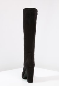 Černé semišové kozačky po kolena s blokovým podpatkem. Mají hladkou texturu a zipové zapínání na boku. Jednoduchý, elegantní design.