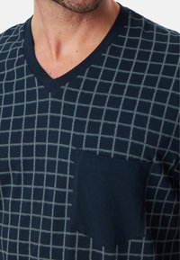 T-shirt blu navy a scollo a V con motivo a rete in azzurro chiaro, dotato di taschino frontale e realizzato in morbido cotone.