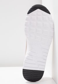 Nike sneaker sole featuring white rubber with textured pattern, black heel section, and prominent brand logo embossed on the rubber.