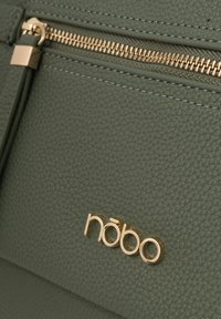 Borsa in pelle texturizzata verde con zip dorata e un accento del logo dorato. Il design è elegante con dettagli di cucitura visibili.