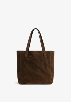 Braune Wildleder-Shopper-Tasche mit langen Henkeln und dezentem GANT-Logo oben in der Mitte, vor weißem Hintergrund gezeigt.