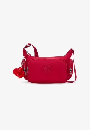 Rode crossbodytas met verstelbare riem, ritssluitingen, gestructureerde stof en een sleutelhangertje in de vorm van een aap.