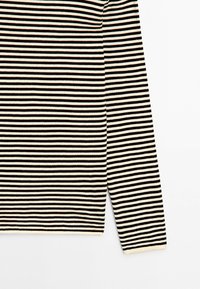 Langarmshirt met smalle horizontale zwarte en witte strepen op een effen achtergrond, waarbij de schouder, het lichaam en één mouw te zien zijn.
