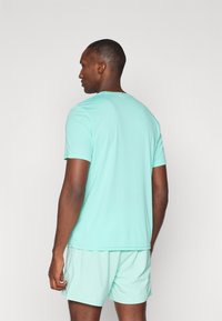 Mint green athletic t-shirt, short-sleeved, smooth texture, paired with matching shorts, viewed from the back. Simple design, no visible logos.
