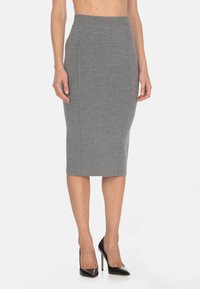 Gonna a matita grigia in maglia con vita alta e cuciture laterali, abbinata a tacchi alti in pelle verniciata nera. Texture liscia e design aderente.