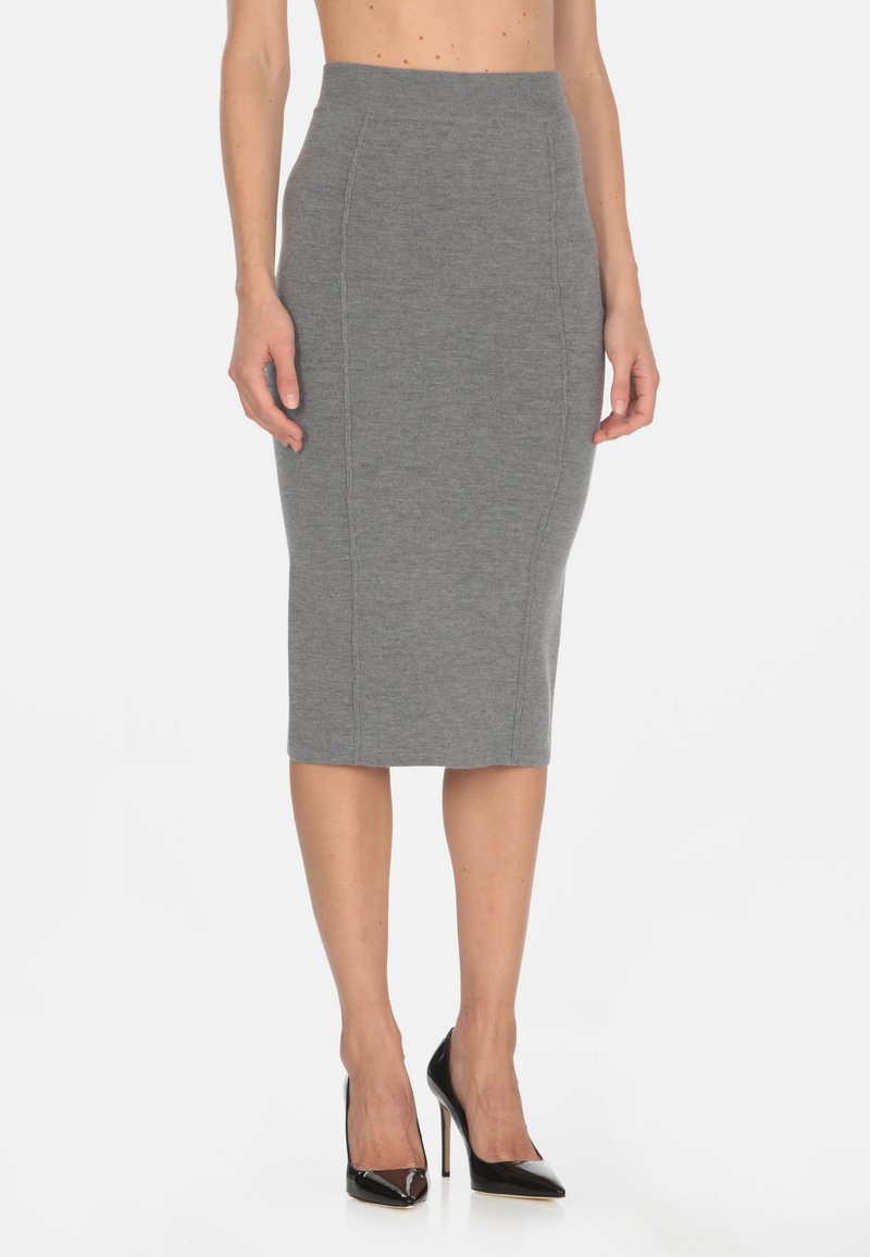 Gonna a matita grigia in maglia con vita alta e cuciture laterali, abbinata a tacchi alti in pelle verniciata nera. Texture liscia e design aderente.