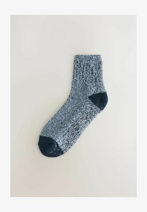 Chaussettes à cheville bleu et blanc avec un revers côtelé, un orteil et un talon bleu foncé, et des points de grip en caoutchouc sur la semelle pour la traction.