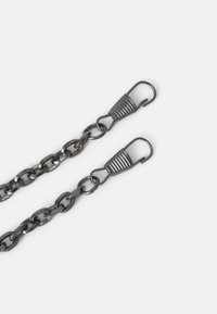 Deux chaînes métalliques noires avec fermoirs à crochet à ressort sur fond blanc.