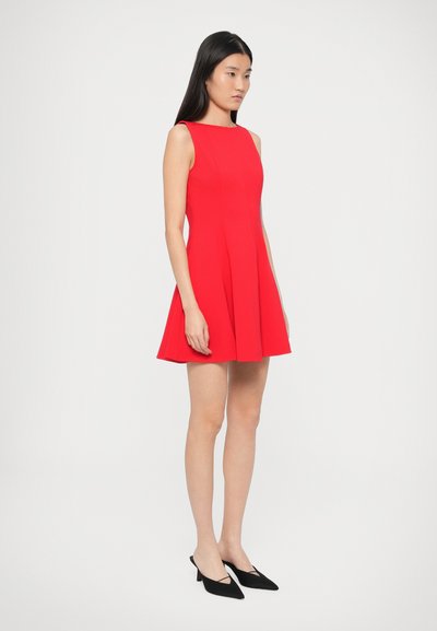 Punane varrukateta kleit, millel on istuv ülakeha ja lõhnav seelik, valmistatud siledast kangast. Sobitatud mustade teravate varbaosaga kontsakingadega.