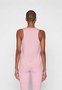 Lys rosa ermeløs tanktopp med rund hals og glatt tekstur, tettsittende design, kombinert med matchende leggings.